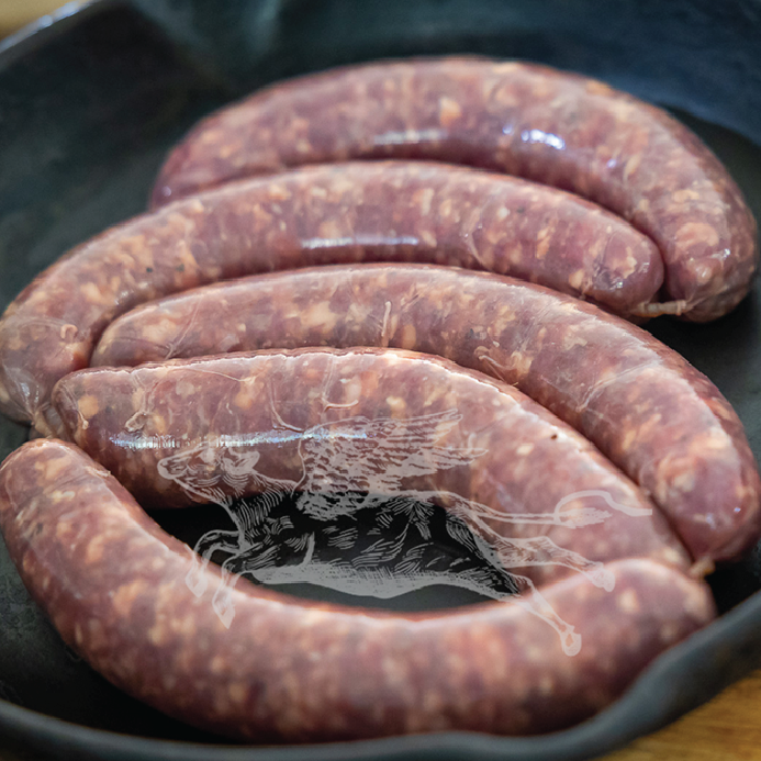 Raw sausages in a black cast iron skillet on a wooden surface