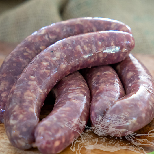 Raw sausages on a wooden cutting board with a blurred background