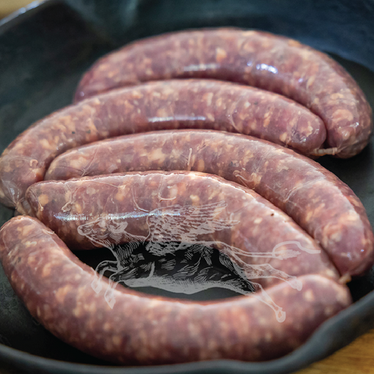 Raw sausages in a black cast iron skillet on a wooden surface